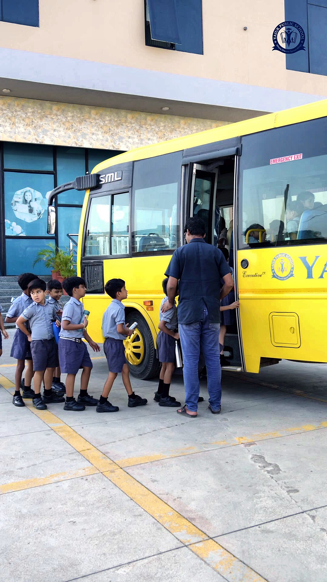 A staff member supervising young students boarding the Yajur school bus