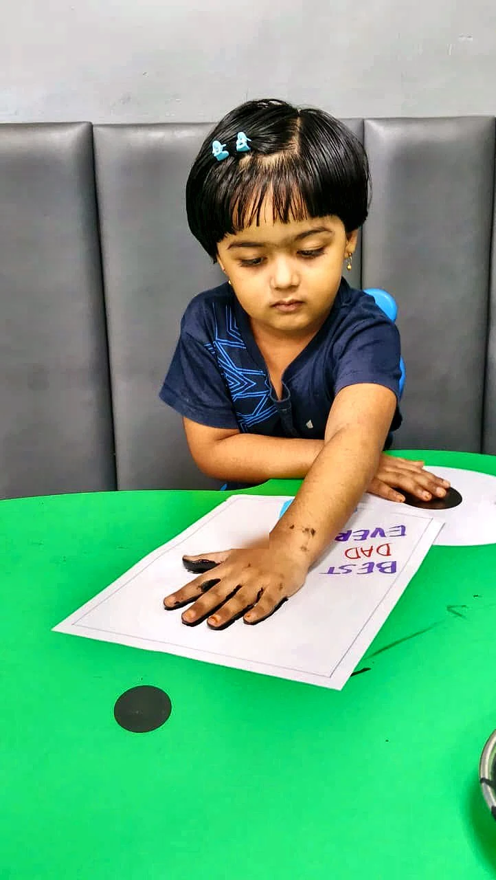 A pre-primary student pressing her handprint onto a card