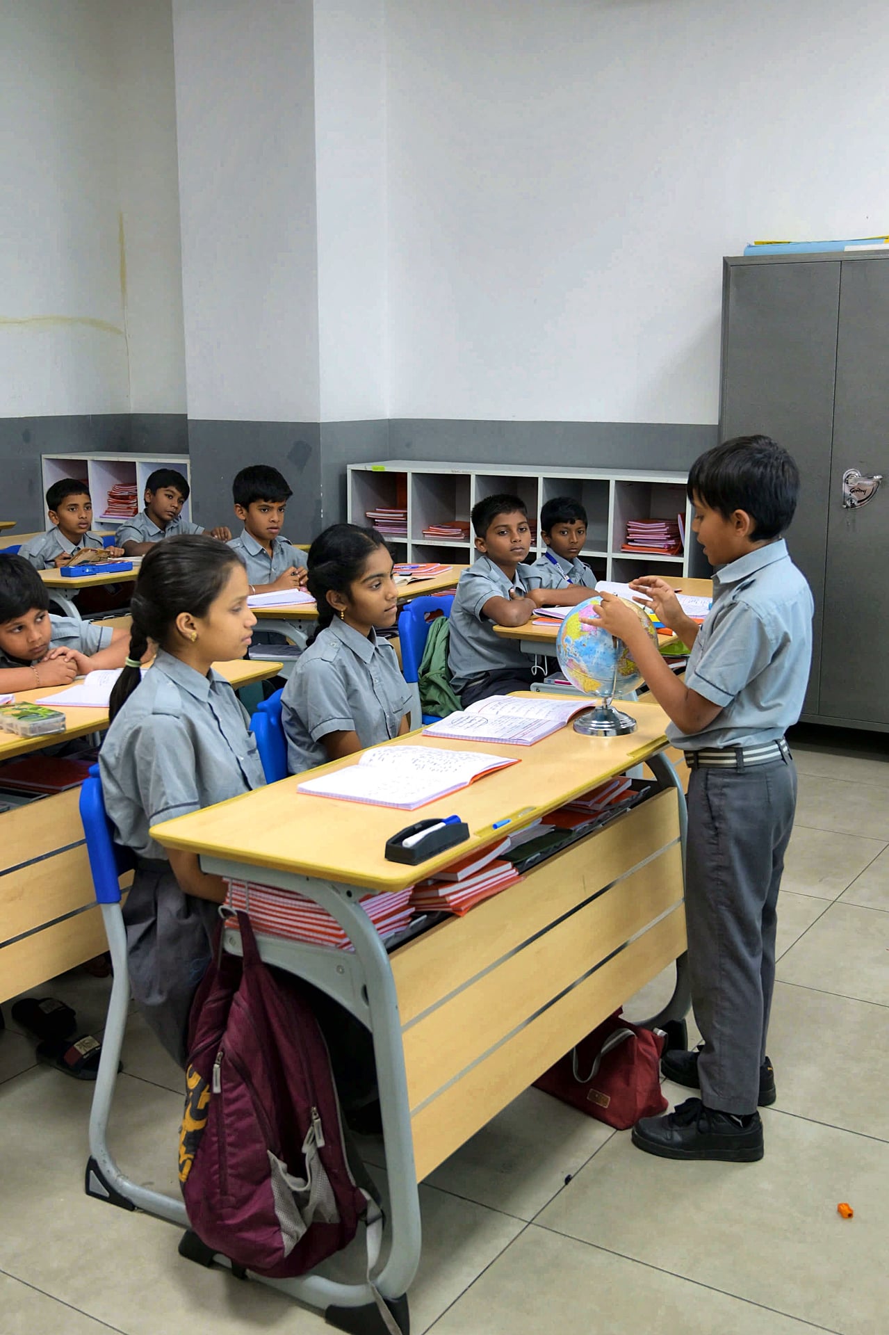 A primary student presenting a globe to his classmates